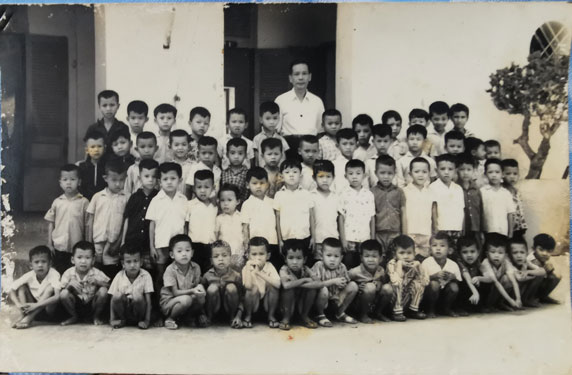 Thầy Nguyễn Văn Bảy và học sinh lớp một năm 1966. Tác giả đứng thứ 7, hàng thứ hai từ trái sang Thầy Nguyễn Văn Bảy và học sinh lớp một năm 1966. Tác giả đứng thứ 7, hàng thứ hai từ trái sang