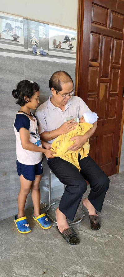 Ông Đinh Minh Nhật bế và cho một bé sơ sinh uống sữa