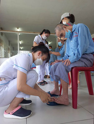 Nhân viên y tế cắt móng chân cho bệnh nhân