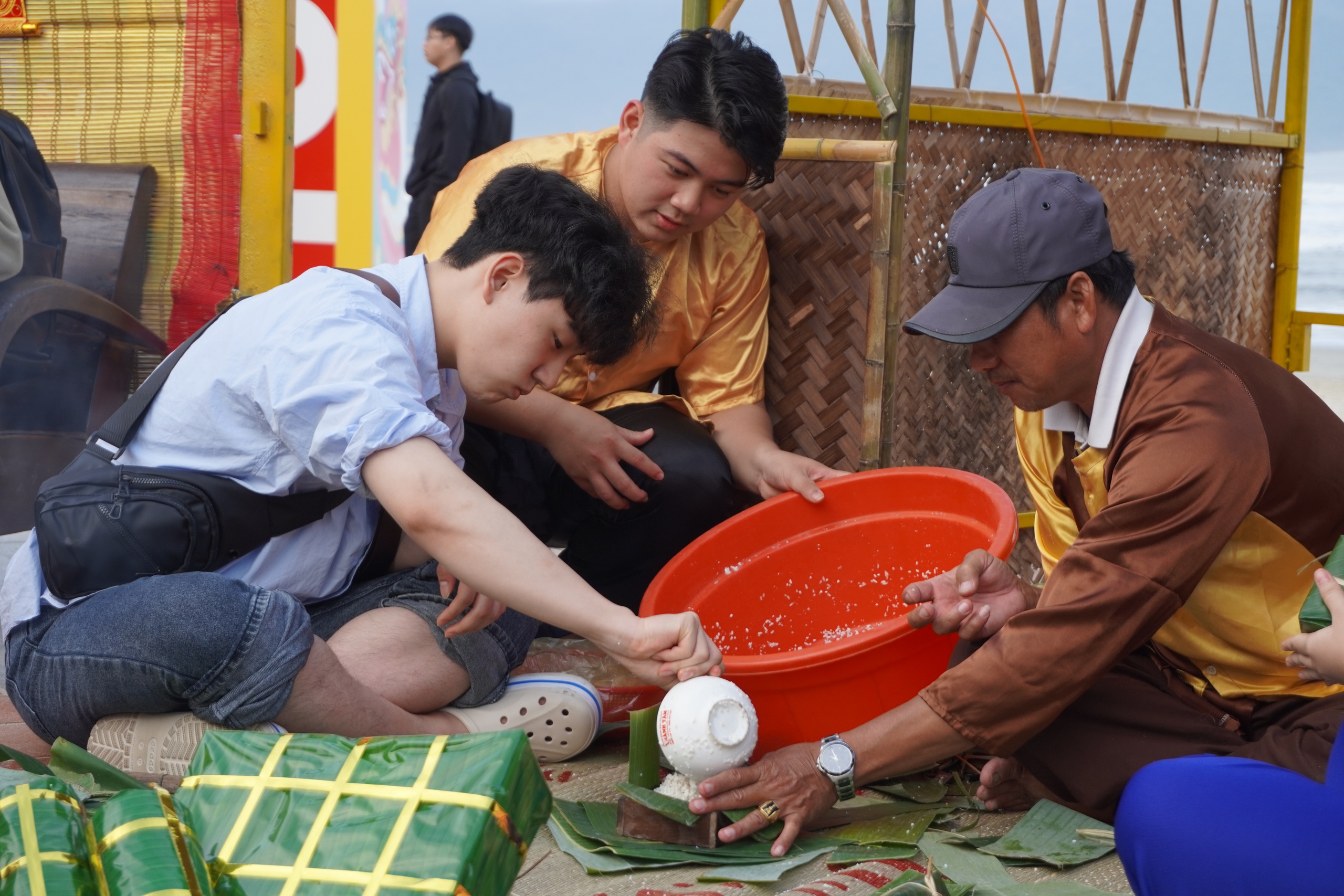 Du khách nước ngoài tập gói bánh chưng bên bãi biển Đà Nẵng- Ảnh 1.