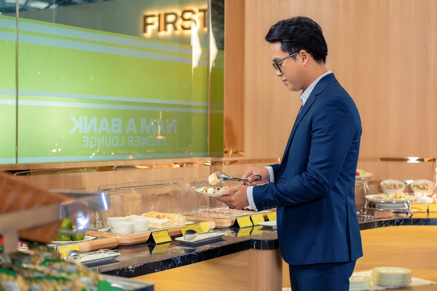 A person in a suit holding food in a glass case  Description automatically generated