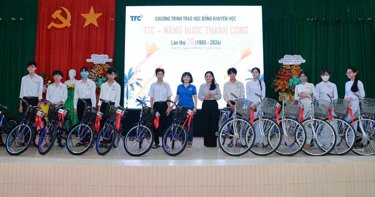 Trao học bổng “TTC - Nâng bước Thành Công” lần thứ 39 năm 2024- Ảnh 2. A group of people standing on a stage with bicycles Description automatically generated