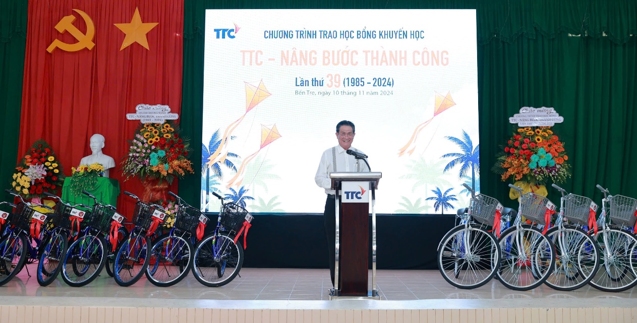Trao học bổng “TTC - Nâng bước Thành Công” lần thứ 39 năm 2024- Ảnh 5. A person standing at a podium with a podium and bicycles on the side Description automatically generated