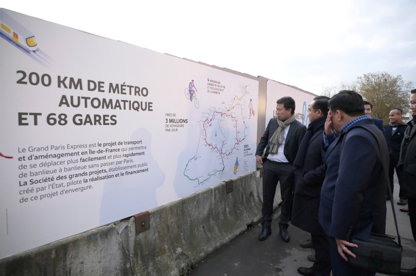 A group of men looking at a sign  Description automatically generated