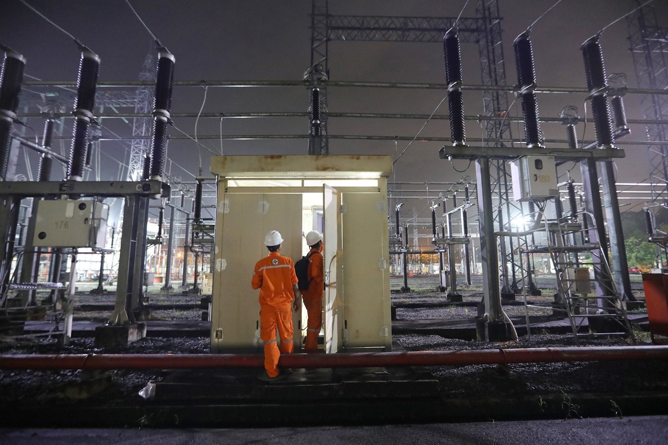 Men in orange jumpsuits standing in a power plant  Description automatically generated