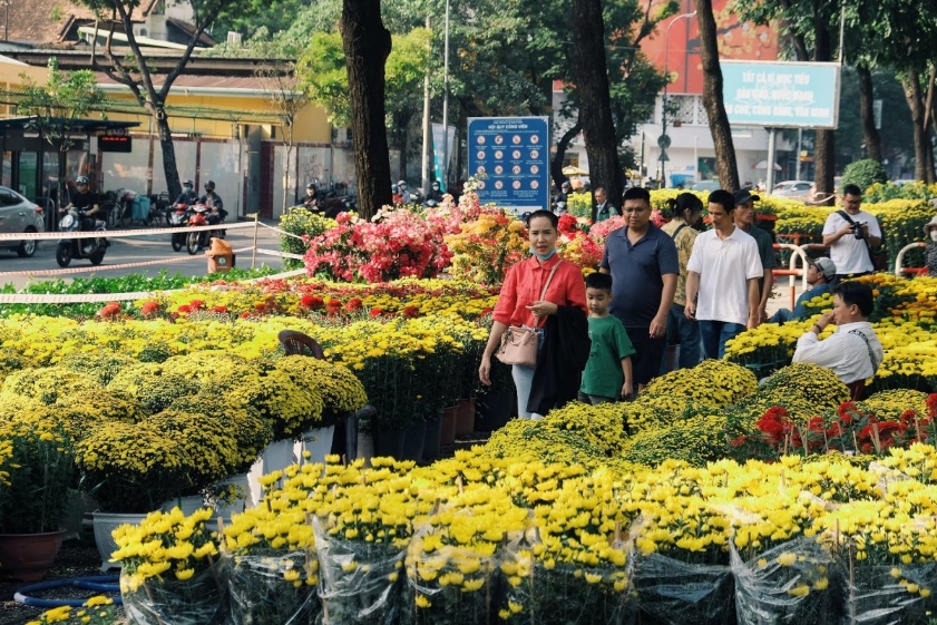 A group of people standing in front of a flower market  Description automatically generated
