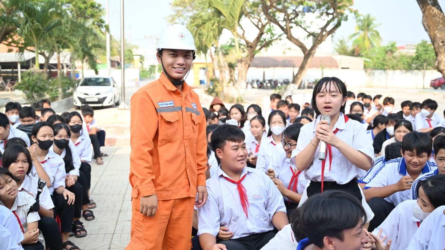 A person in an orange jumpsuit standing in front of a group of people  Description automatically generated