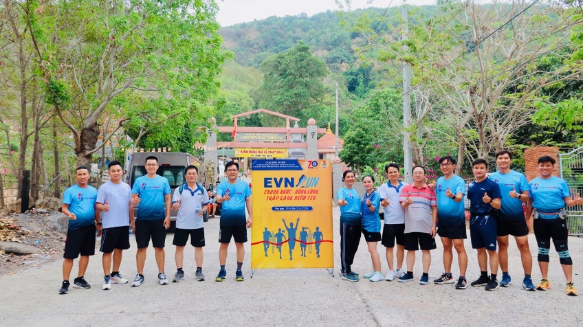 A group of people standing in front of a sign  Description automatically generated