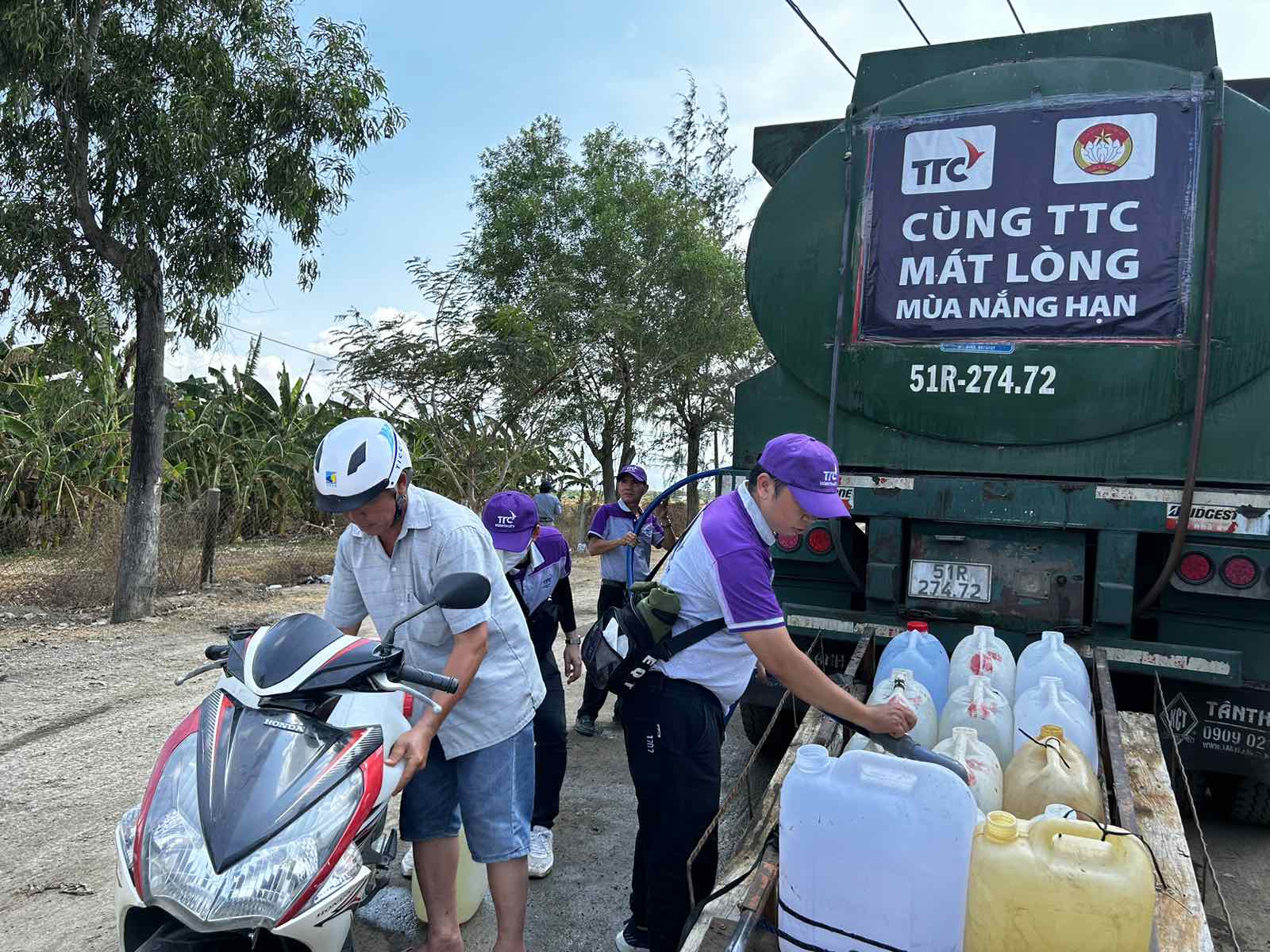 A group of people loading water into a truck  Description automatically generated