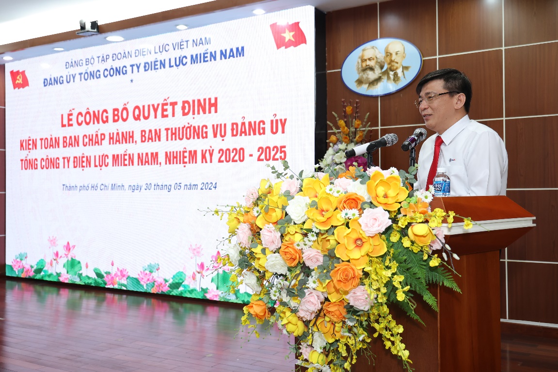 A person standing at a podium with a large white sign with flowers  Description automatically generated