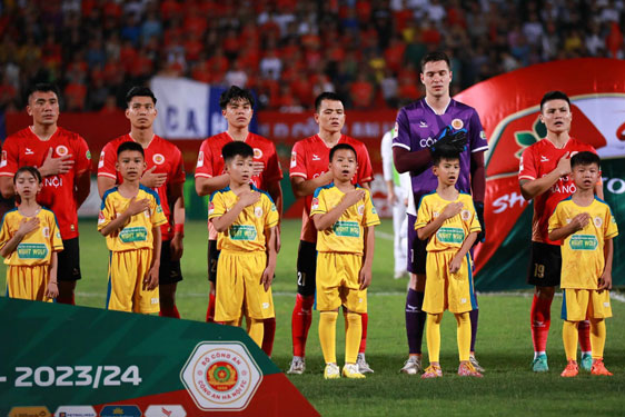 Các em nhỏ dân tộc thiểu số ở huyện Hoàng Su Phì (Hà Giang) đứng cạnh các ngôi sao CLB Công an Hà Nội trong nghi thức chào cờ trước trận đấu tại V-League đầu tháng 4-2024