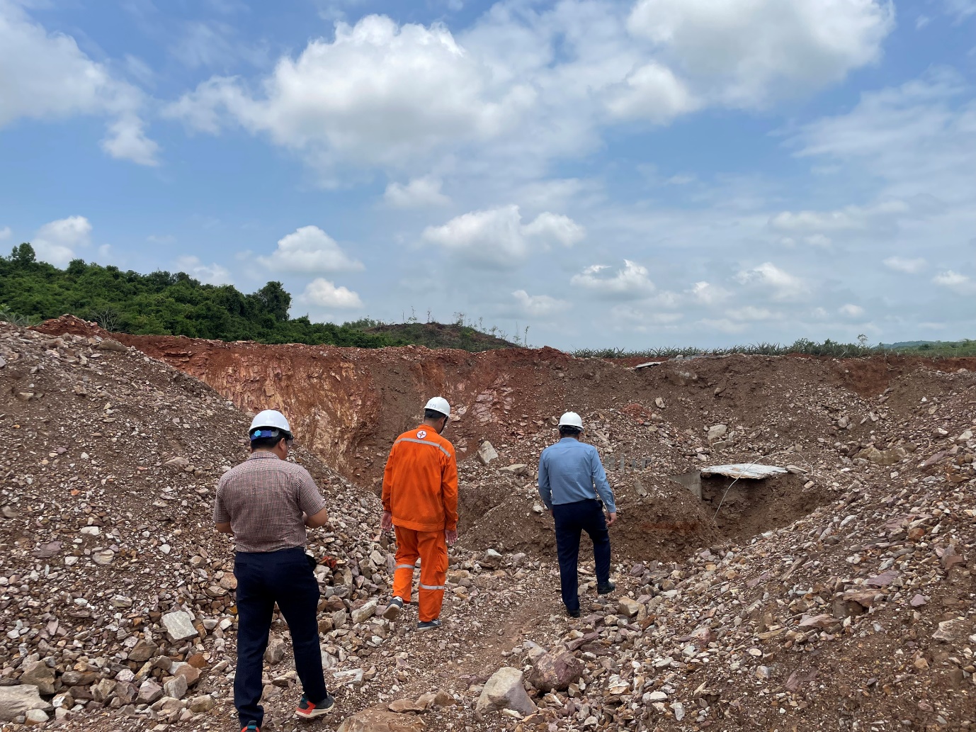 A group of men in hard hats in a rocky area  Description automatically generated