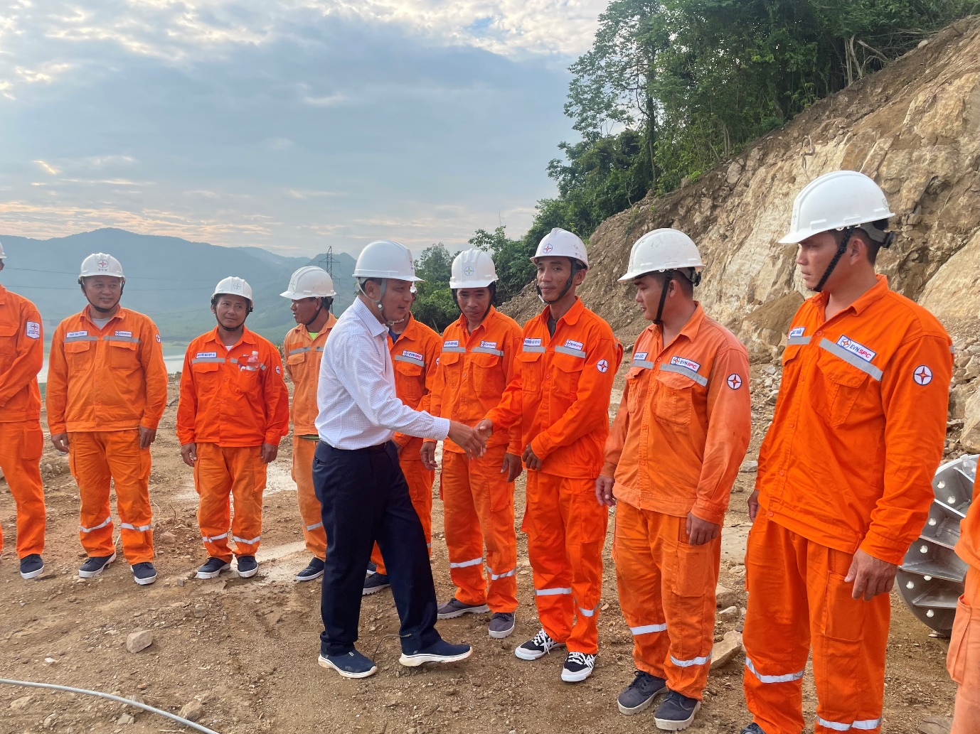 A group of people in orange jumpsuits and helmets shaking hands  Description automatically generated