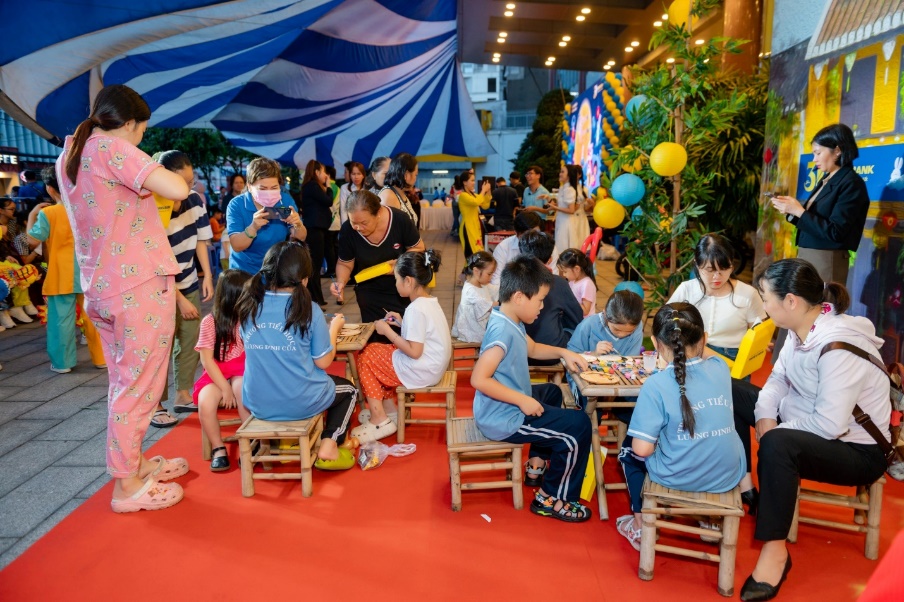 A group of children sitting at tables in a tent  Description automatically generated