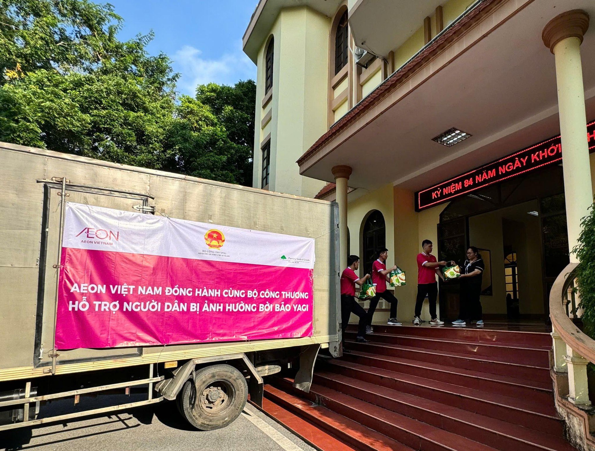 A truck with a sign on it outside of a building  Description automatically generated