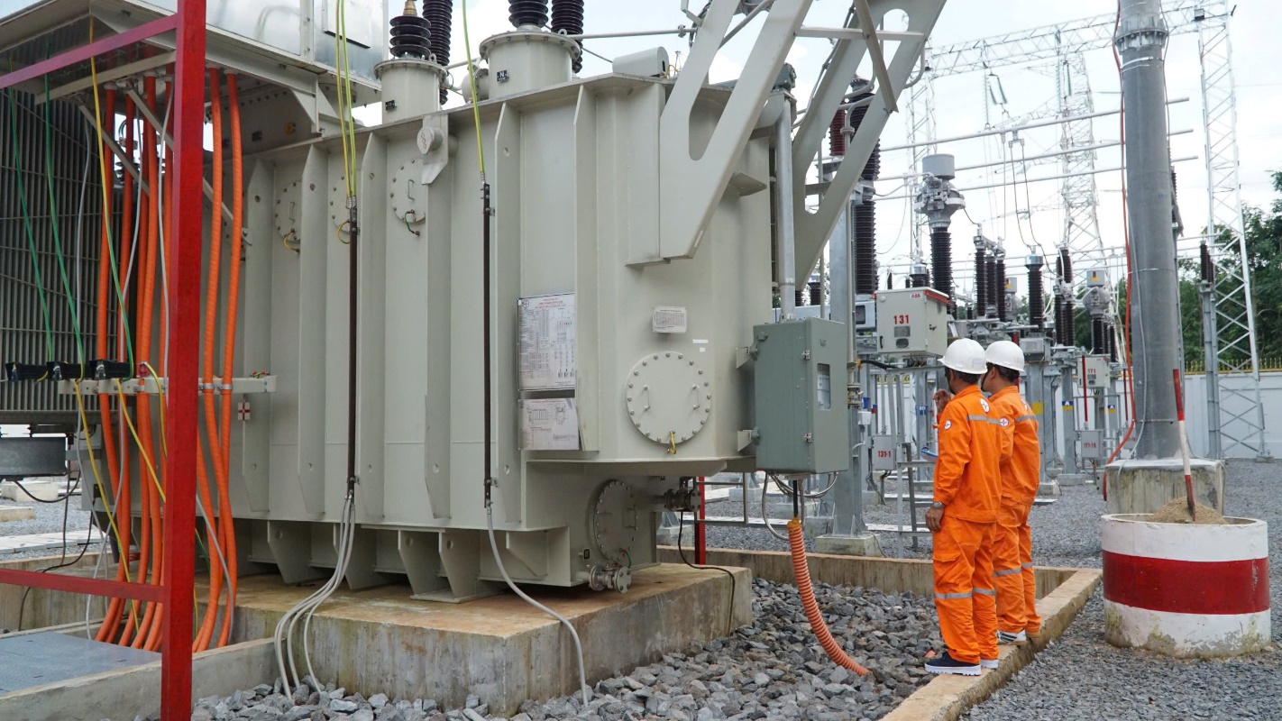 A group of men in orange jumpsuits standing next to a large machine  Description automatically generated