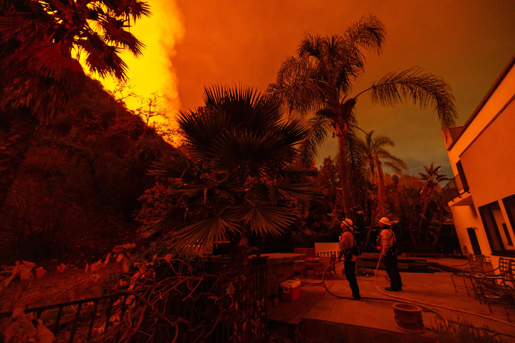 Firefighters stand guard at a home on Mandeville Canyon Road