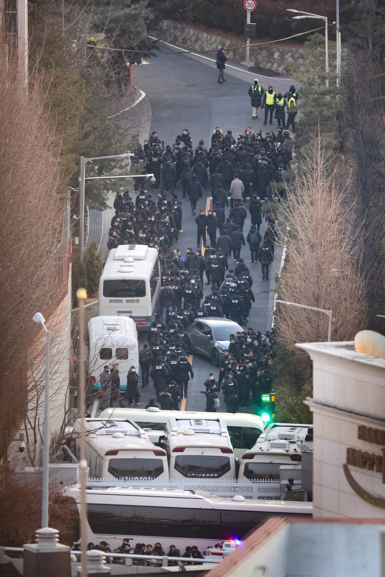 Investigators attempting to arrest suspended President Yoon Suk Yeol move past a barricade of buses set up by the Presidential Security Service inside the gates of the presidential residence compound in Hannam-dong, Yongsan-gu, Seoul on Wednesday. (Yonhap)