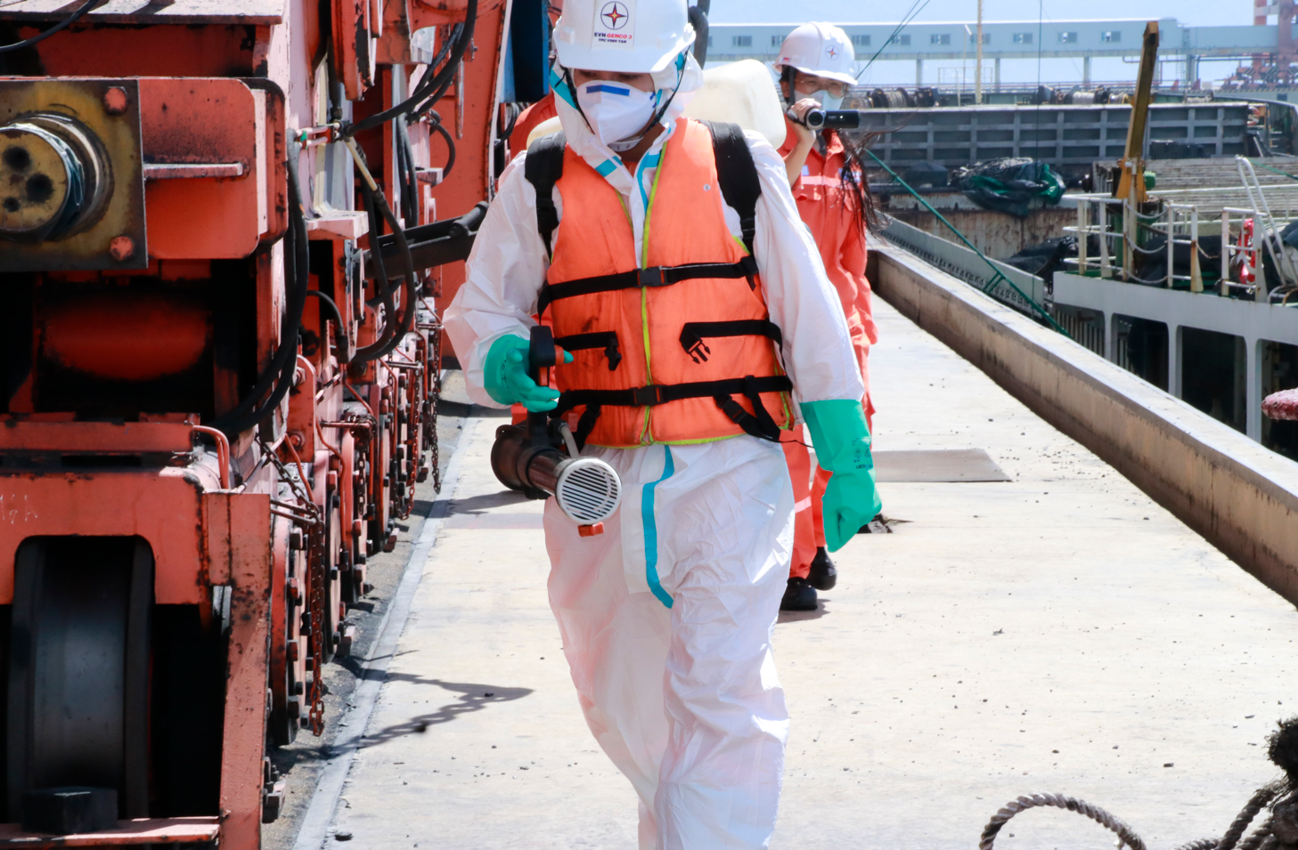 A person in a white protective suit and helmet walking on a dock  AI-generated content may be incorrect.