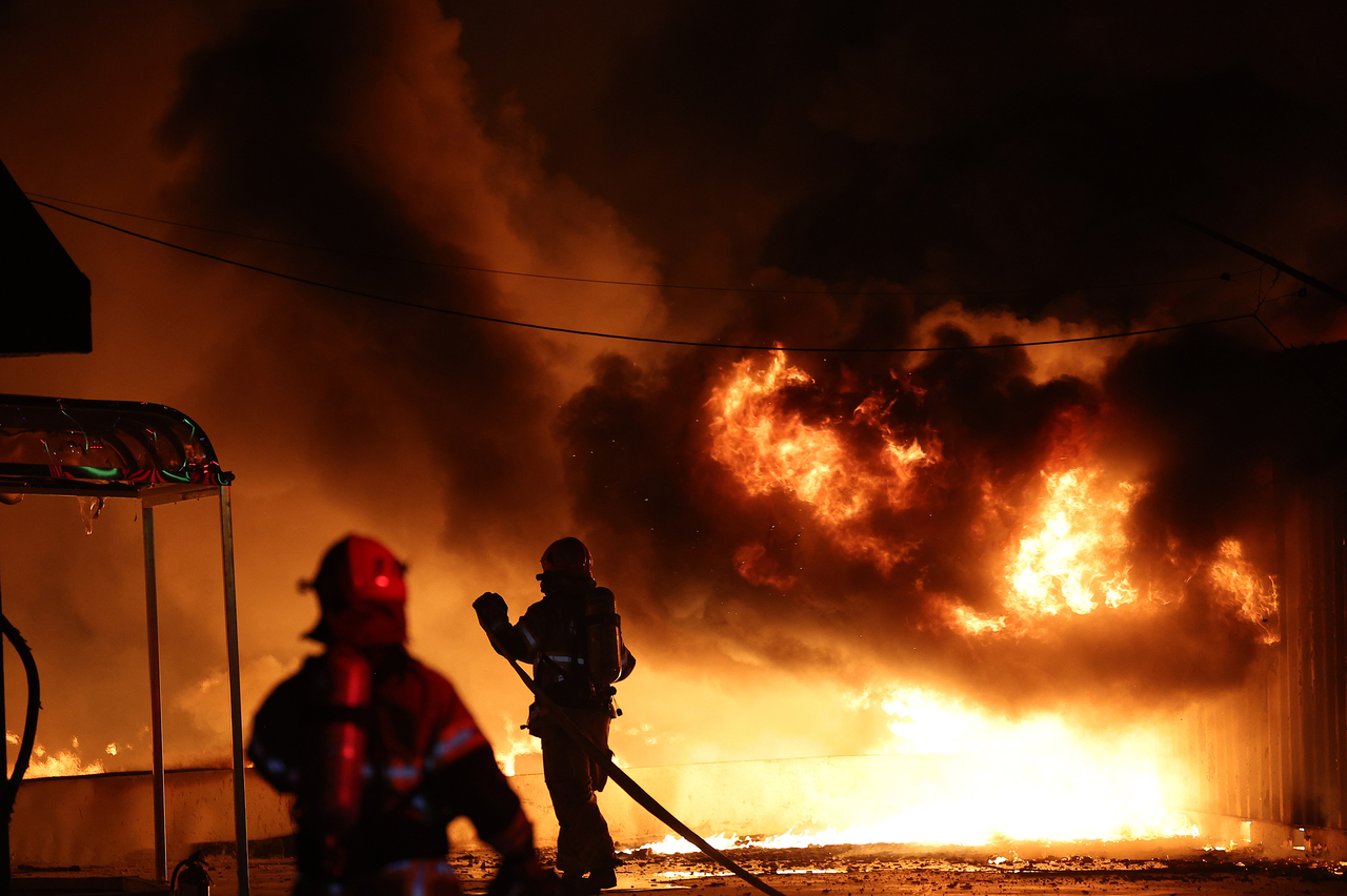 Firefighters extinguish a fire at a factory building that has been engulfed in a wildfire in Uiseong County, North Gyeongsang Province, on Saturday. (Yonhap)