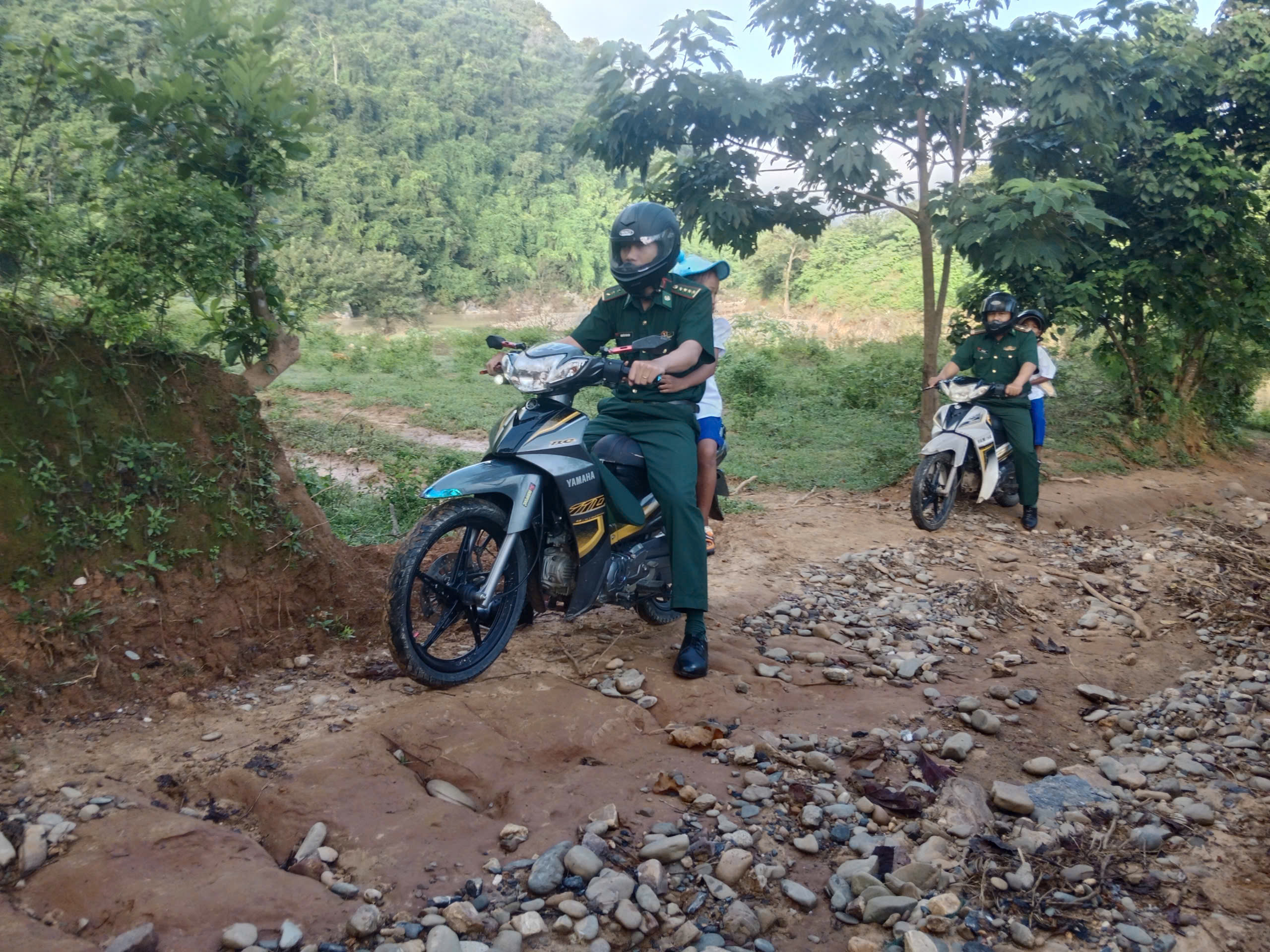 Grenswachters van Quang Tri dragen leerlingen over de beken naar school voor de openingsceremonie van het nieuwe schooljaar - Foto 1. Biên phòng Quảng Trị cõng học sinh vượt suối đến trường khai giảng năm học mới - Ảnh 1.