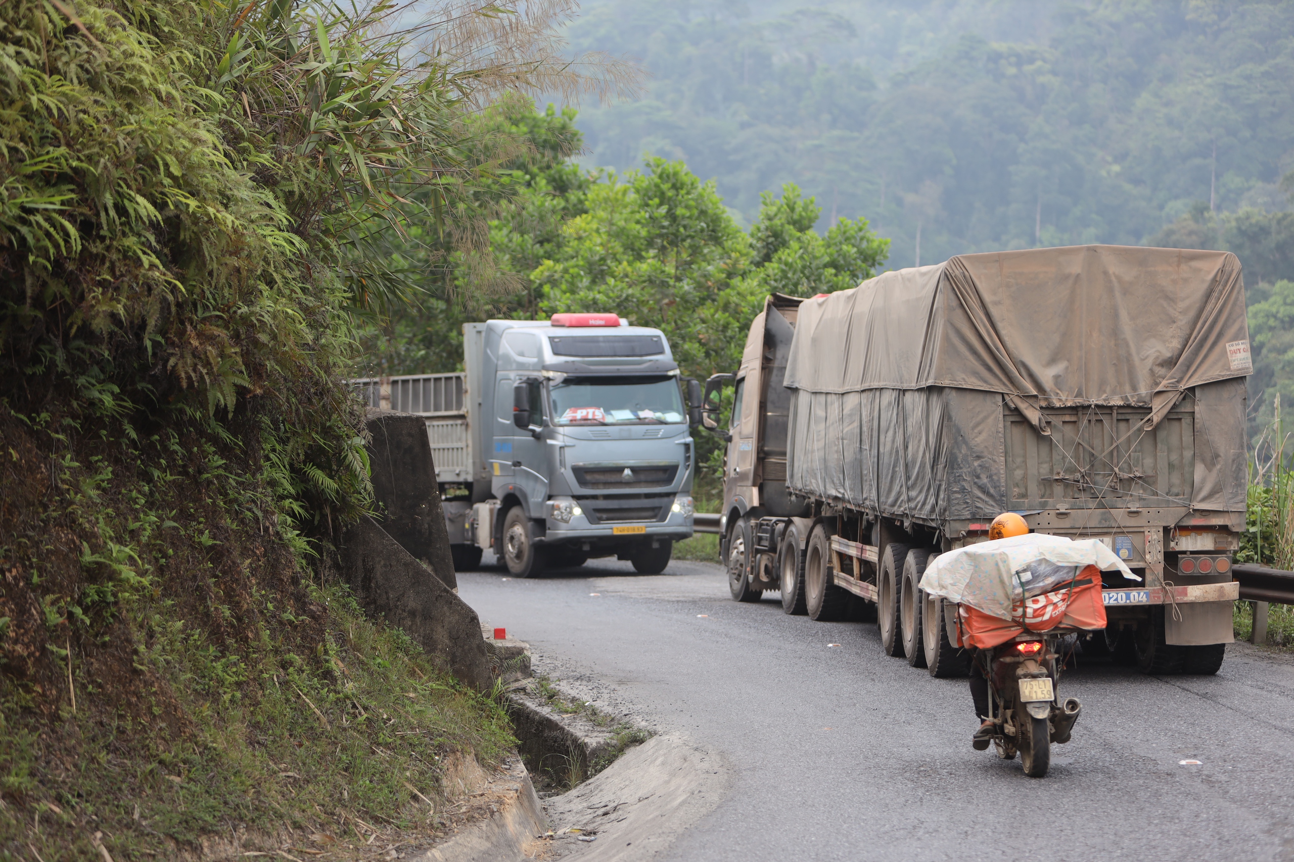 Đường hẹp, đèo dốc, gặp xe đầu kéo người đi xe máy chỉ biết... ép mình vào lan can - Ảnh 1.