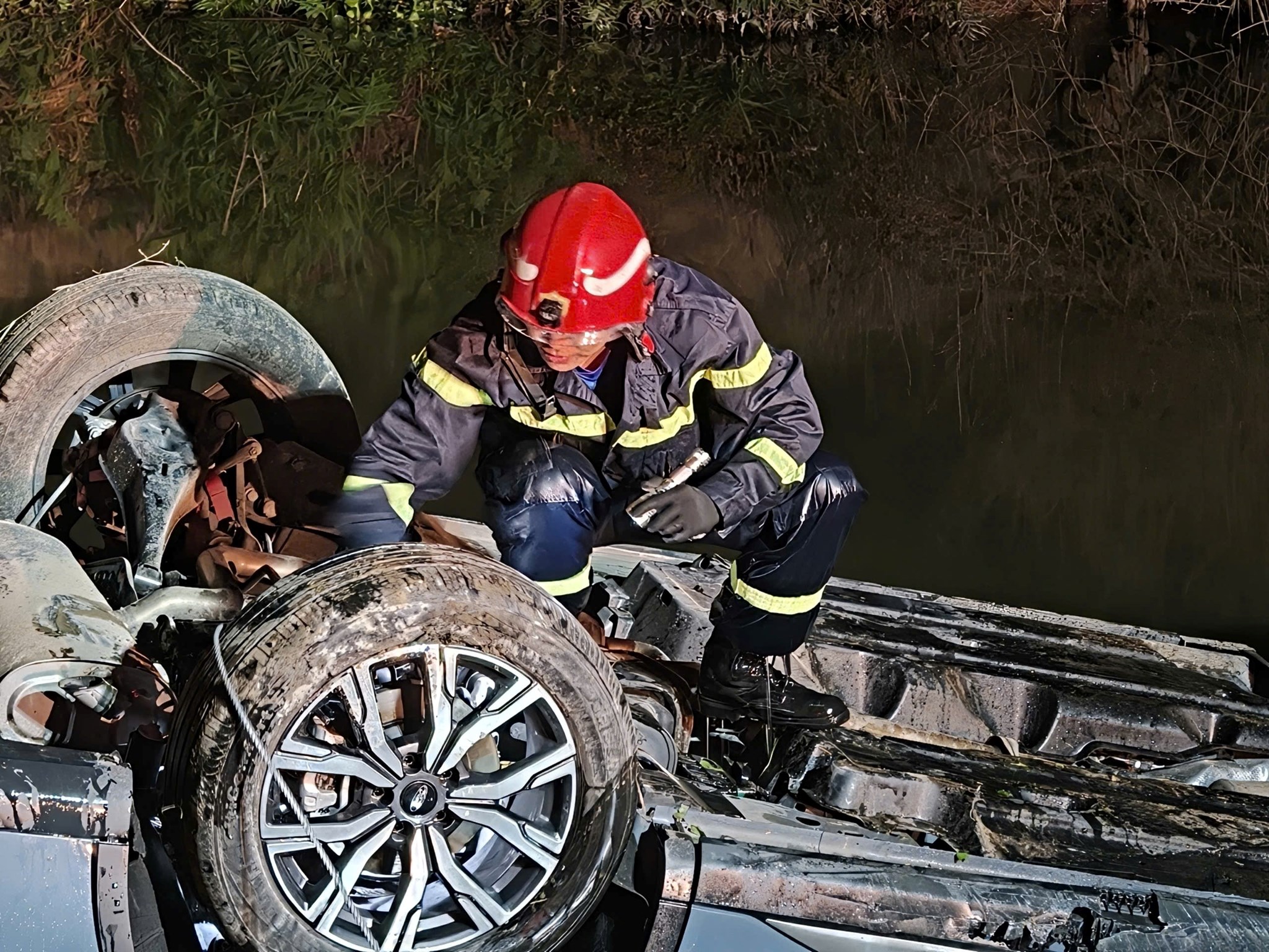 Cứu hộ nam thanh niên mắc kẹt trong xe ô tô nằm ngửa bụng dưới mương nước hàng giờ - Ảnh 1.