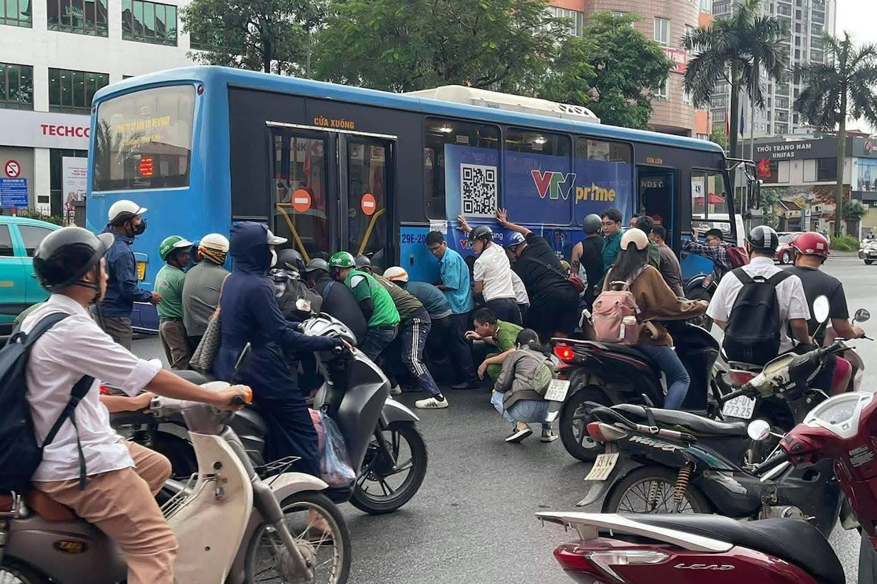 Gần 20 người nâng xe buýt cứu người phụ nữ mắc kẹt dưới gầm - Ảnh 1.