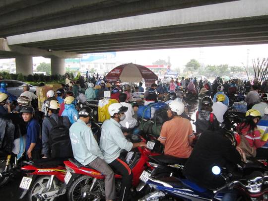 Trong khi đó, tại gầm cầu vượt Tân Sơn Nhất - Bình Lợi - Vành đai ngoài, hàng trăm người vô tư đậu xe ở giữa lòng đường đứng trú mưa làm giao thông qua đây tắc nghẽn