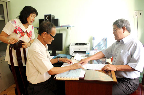 Ông Nguyễn Văn Tính (phải) hướng dẫn thân nhân ngư dân gặp nạn trên biển làm thủ tục xin hỗ trợ