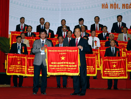 Thủ tướng Nguyễn Tấn Dũng trao cờ của Chính phủ cho nhân dân và cán bộ huyện, xã xuất sắc trong phong trào thi đua “Cả nước chung sức xây dựng nông thôn mới” giai đoạn 2011-2015Ảnh: TTXVN