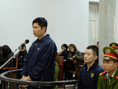 Bị cáo Nguyễn Mạnh Tường đứng trước vành móng ngựa và bị cáo Đào Quang Khánh (ngồi) tại phiên tòa sơ thẩm
