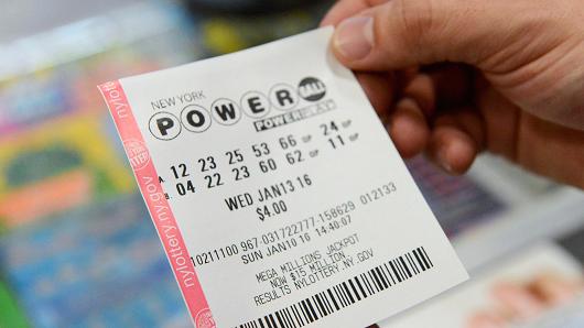 Một người dân cầm tờ vé số Powerball phát hành hôm 13-1. Ảnh: Reuters