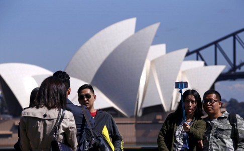 Du khách Trung Quốc chụp hình trước Nhà hát Opera ở TP Sydney - Úc. Ảnh: Reuters