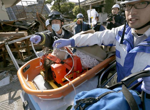 Lực lượng cứu hộ đưa một phụ nữ ra khỏi căn nhà bị đổ sập ở thị trấn Mashiki, tỉnh Kumamoto ngày 16-4 Ảnh: REUTERS