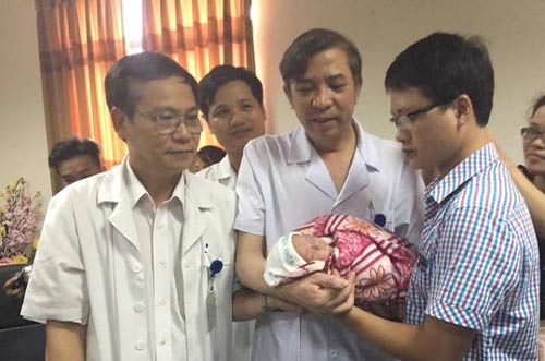 Bác sĩ trao bé Gấu cho bố Trần Mạnh Hà (bìa phải) trong ngày xuất viện Ảnh: NGỌC DUNG