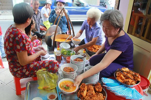 Vì diện tích nhỏ nên hai ghế chồng lên nhau làm bàn, mỗi người ngồi ăn như gánh hàng rong Ảnh: Bùi Thư