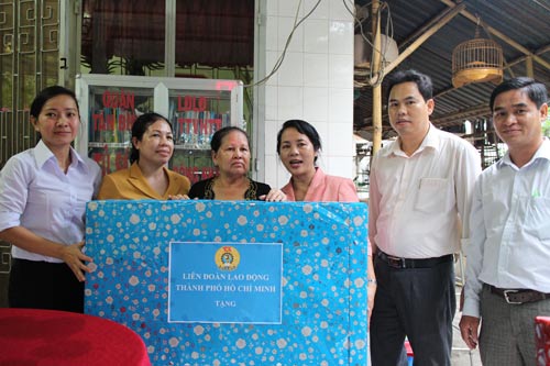 
Bà Huỳnh Thị Em (thứ ba từ trái sang) nhận quà do bà Trần Kim Yến, Chủ tịch LĐLĐ TP HCM, trao tặng.
