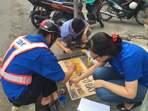 Các đoàn viên vẽ dòng chữ “Đừng bỏ rác ở đây - rác làm tắc cống gây ngập nước”