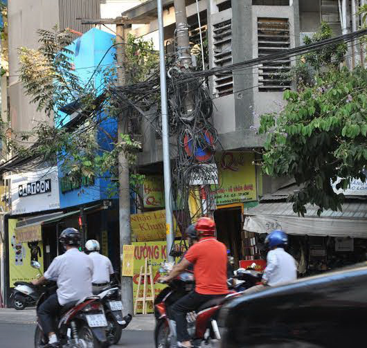 Một góc ngã tư Trần Phú - Trần Bình Trọng, quận 5, TP HCM, biển báo bị dây điện bao vây