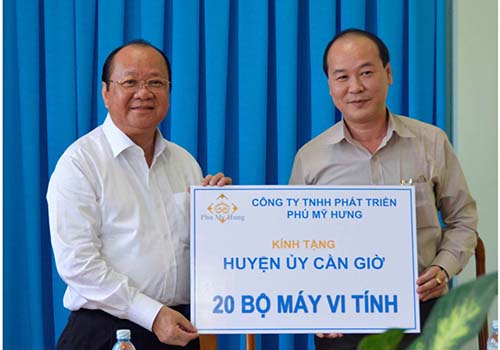 Ông Nguyễn Bửu Hội, Phó Tổng Giám đốc Công ty TNHH Phát triển Phú Mỹ Hưng (trái), trao tặng 20 bộ máy vi tính cho huyện Cần Giờ
