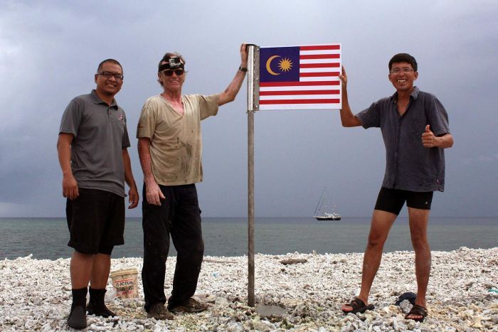 
Ông Hans Berekoven (giữa) và những người bạn Malaysia cắm cờ Malaysia trên bãi Luconia. Ảnh: ABC
