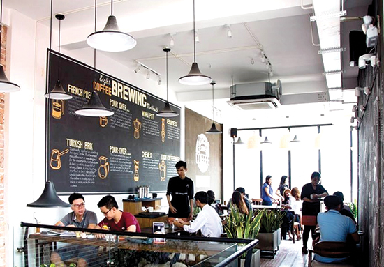 Không gian bài trí hiện đại với nhiều cây xanh bên trong một quán cà phê thương hiệu The Coffee House.