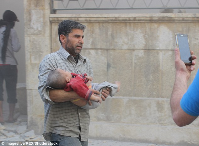 
Chỉ trong vòng chưa đầy 24 giờ, hai hình ảnh cho thấy sự tàn khốc nhất của cuộc chiến Syria nổi lên trên báo chí thế giới. Trong ảnh là bé trai bị thương đang ở trong vòng tay cha sau cuộc không kích hôm 18-8 ở Aleppo. Ảnh: Daily Mail
