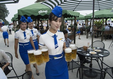 Những vị khách du lịch cùng người dân tận hưởng không khí thân thiện của lễ hội với các phục vụ trong bộ đồng phục màu xanh, trên tay cầm theo những cốc bia lớn.