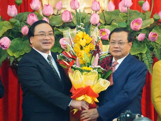 Ông Phạm Quang Nghị (phải) tặng hoa chúc mừng tân Bí thư Hà Nội Hoàng Trung Hải trong ngày nhậm chức