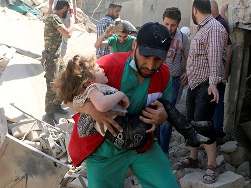 Một em bé được cứu sống từ đống đổ nát ở Aleppo hôm 28-4 Ảnh: REUTERS