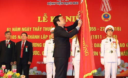 Chủ tịch nước Trương Tấn Sang gắn Huân chương Độc lập hạng ba lên lá cờ truyền thống của Bệnh viện Bạch Mai Ảnh: TTXVN