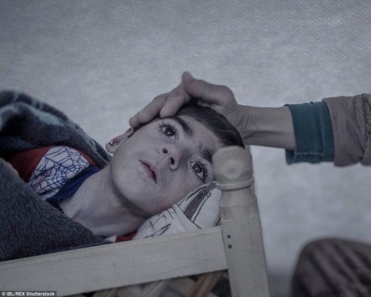 
Shiraz, 9 tuổi, mắc chứng bại liệt khi mới được 3 tháng tuổi. Cô bé đang ngủ trong một cái nôi bằng gỗ tại một trại tị nạn ở Suruç, Thổ Nhĩ Kỳ. Cha mẹ em không đủ tiền mua thuốc vì chạy miếng ăn đã là khó khăn. Ảnh: IBL
