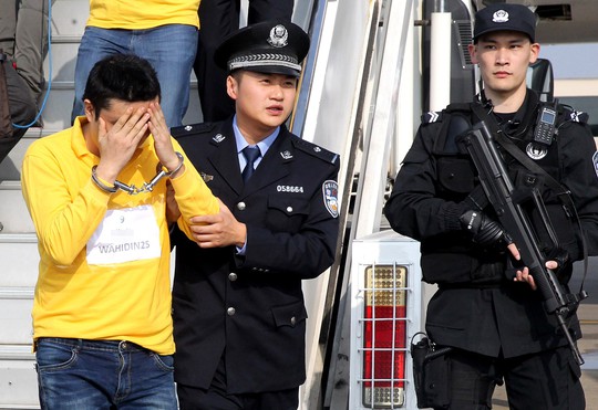 Một nghi phạm bị áp giải về Trung Quốc hôm 10-11. Ảnh: Tân Hoa Xã